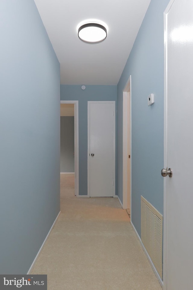 hall with light carpet, baseboards, and visible vents