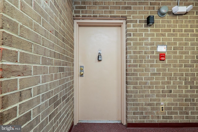 doorway to property featuring brick siding