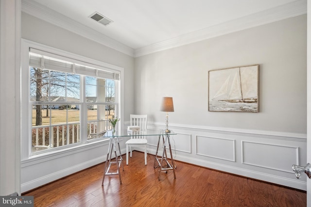 office space featuring a wainscoted wall, visible vents, wood finished floors, and ornamental molding