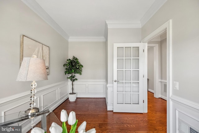 interior space with visible vents, wainscoting, wood finished floors, crown molding, and a decorative wall