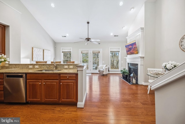 kitchen featuring dark wood-style flooring, light stone countertops, vaulted ceiling, a fireplace, and a sink