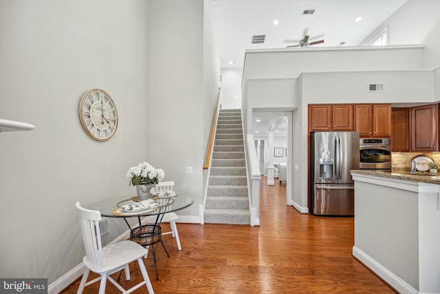 kitchen featuring stainless steel appliances, backsplash, wood finished floors, and visible vents