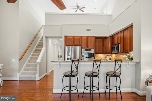 kitchen with stainless steel appliances, a breakfast bar, visible vents, and a peninsula