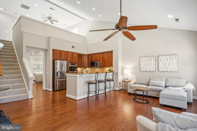 living room featuring ceiling fan, stairs, visible vents, and wood finished floors