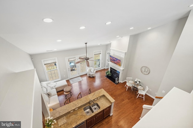 living area featuring baseboards, a fireplace with flush hearth, ceiling fan, dark wood-type flooring, and recessed lighting