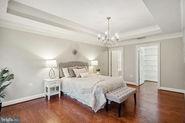 bedroom featuring baseboards, visible vents, a tray ceiling, and wood finished floors