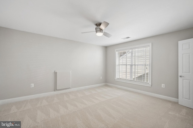 spare room with baseboards, visible vents, and light colored carpet