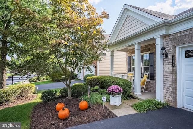 property entrance with a porch and brick siding