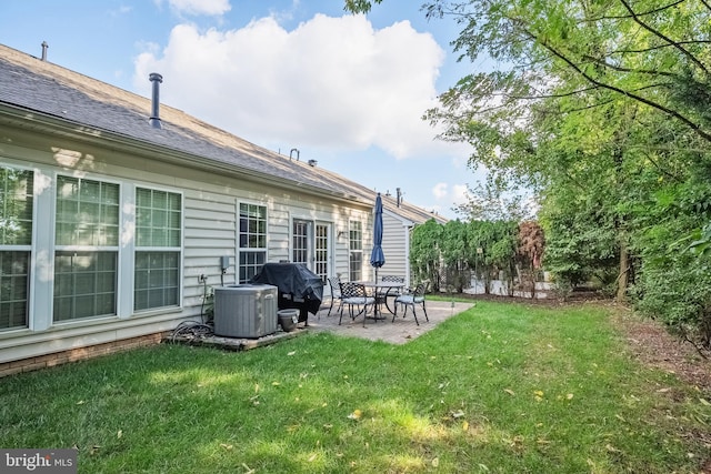 back of house with a shingled roof, a lawn, a patio area, and cooling unit