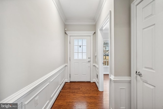 doorway to outside with ornamental molding, dark wood-style flooring, wainscoting, and a decorative wall