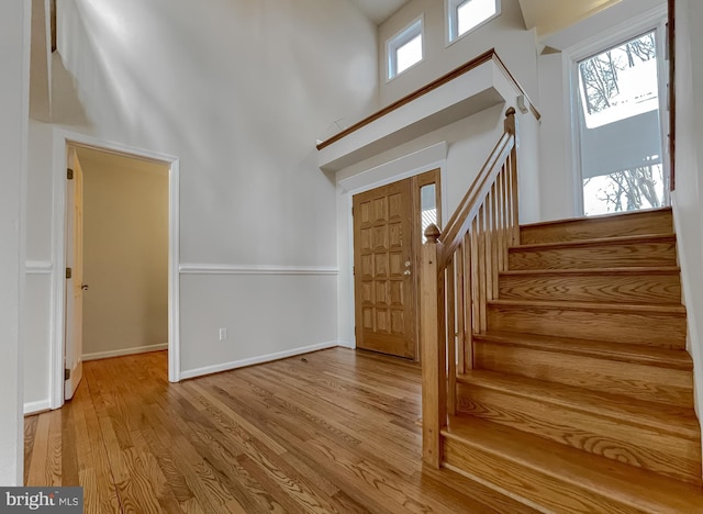 entryway with stairs, a high ceiling, baseboards, and wood finished floors