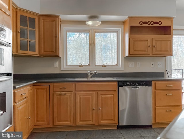 kitchen with stainless steel appliances, dark countertops, and a sink