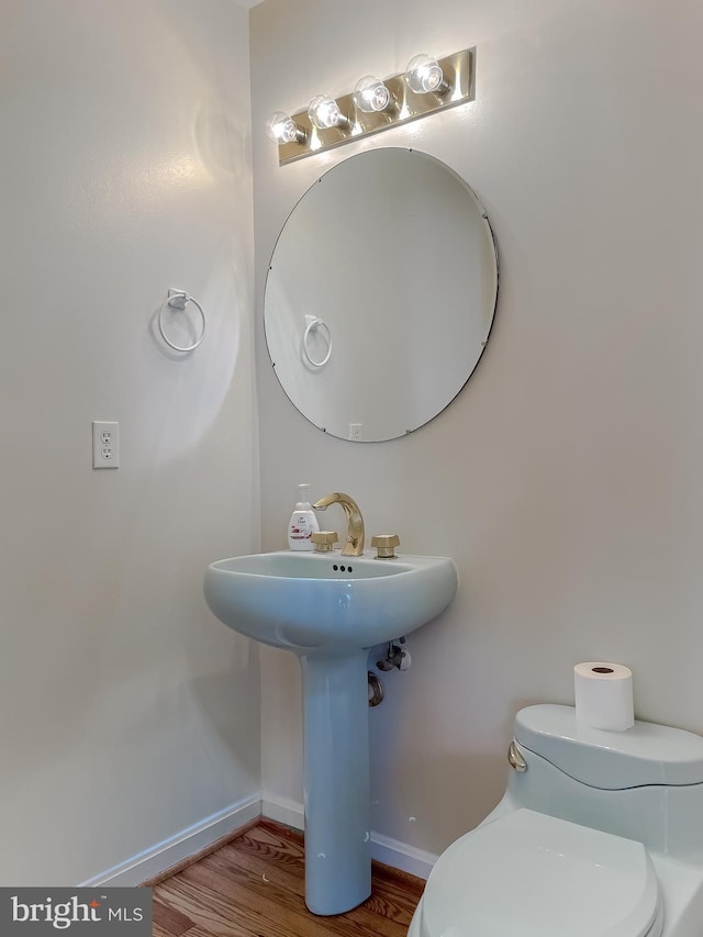 half bath with wood finished floors, toilet, and baseboards