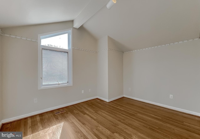 additional living space with visible vents, vaulted ceiling with beams, baseboards, and wood finished floors