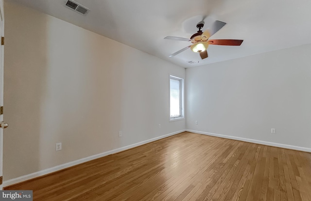 unfurnished room with baseboards, visible vents, ceiling fan, and hardwood / wood-style floors