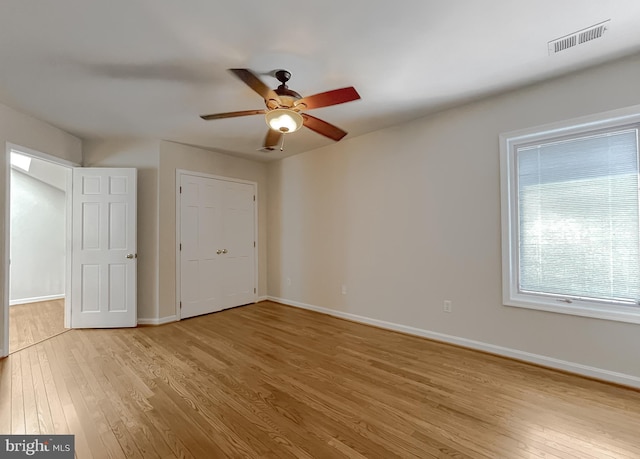 unfurnished bedroom featuring ceiling fan, light wood finished floors, visible vents, and baseboards