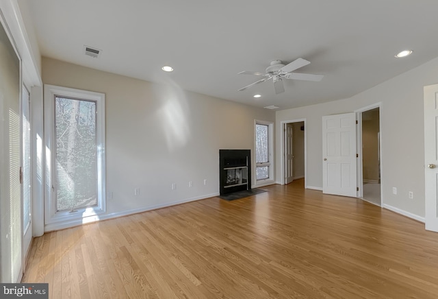 unfurnished living room featuring a fireplace with flush hearth, recessed lighting, light wood-style flooring, and baseboards