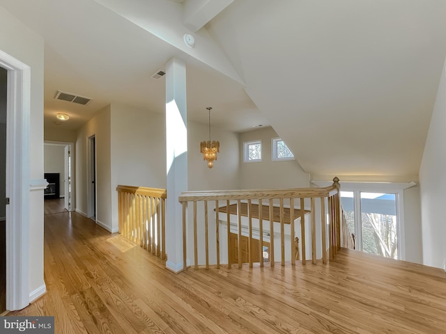 additional living space featuring baseboards, wood finished floors, visible vents, and a notable chandelier