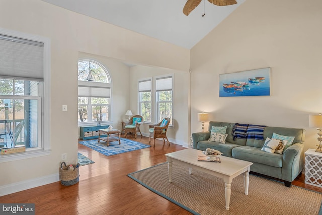 living area featuring ceiling fan, baseboards, high vaulted ceiling, and wood finished floors