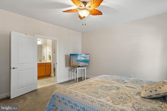 bedroom featuring light carpet, ensuite bath, baseboards, and a sink