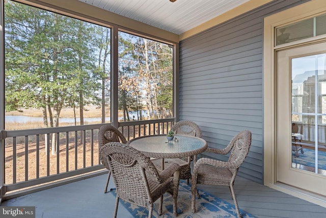 sunroom featuring a water view