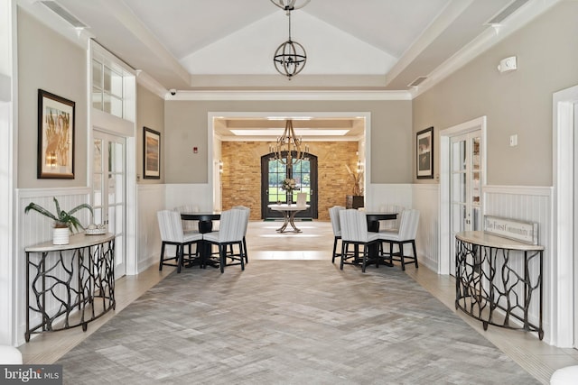 interior space with wainscoting, lofted ceiling, and an inviting chandelier