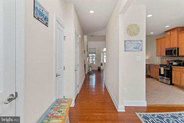 corridor featuring recessed lighting, baseboards, and light wood-style flooring