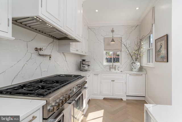 kitchen featuring a sink, high end stove, white cabinetry, and crown molding