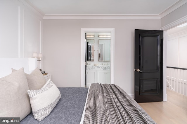 bedroom featuring ornamental molding, ensuite bath, and wood finished floors