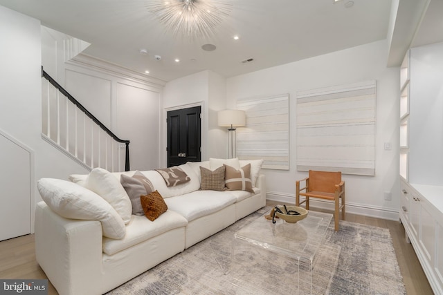 living area featuring recessed lighting, a notable chandelier, wood finished floors, visible vents, and stairs