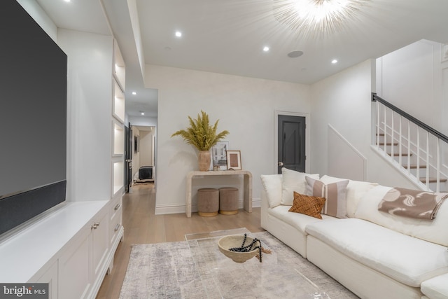 living room featuring light wood-style floors, recessed lighting, and stairs