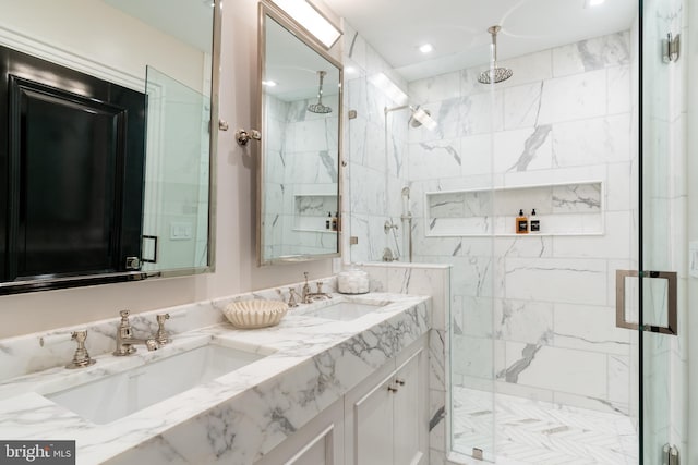 full bathroom featuring double vanity, a sink, and a marble finish shower