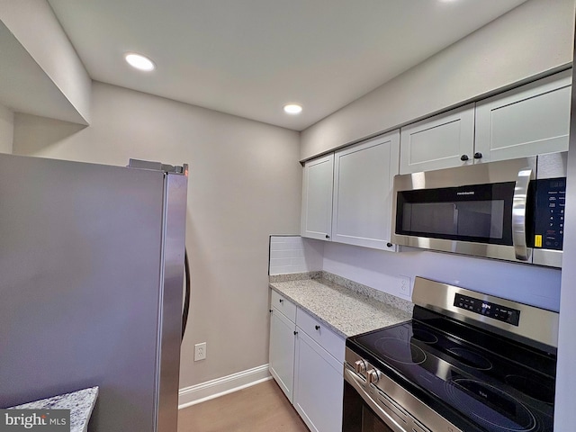 kitchen with baseboards, white cabinets, light wood-style flooring, appliances with stainless steel finishes, and recessed lighting