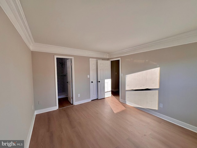 unfurnished room with ornamental molding, wood finished floors, and baseboards