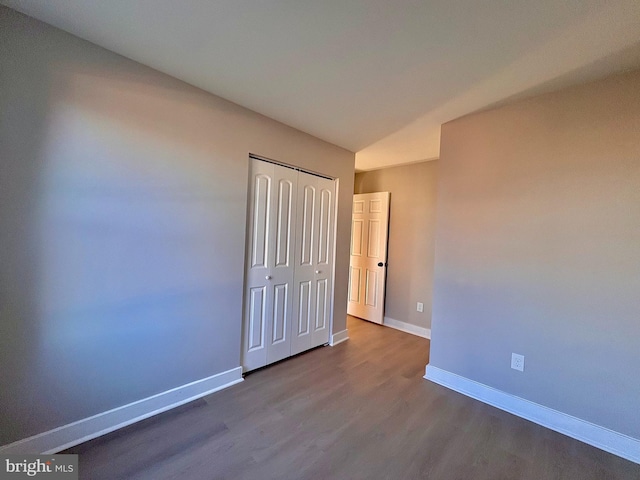 unfurnished bedroom featuring a closet, baseboards, and wood finished floors