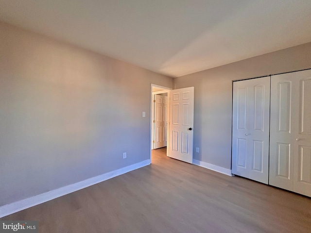 unfurnished bedroom with light wood-style floors, a closet, and baseboards