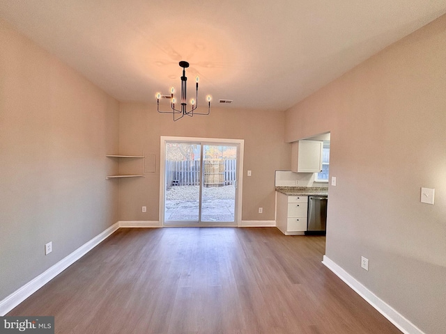 unfurnished dining area with a chandelier, wood finished floors, visible vents, and baseboards