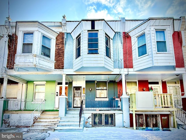 townhome / multi-family property with stairs, a porch, and brick siding