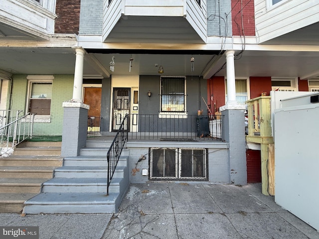 property entrance featuring a porch and brick siding