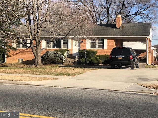 view of front of property with driveway, a chimney, an attached carport, roof with shingles, and brick siding