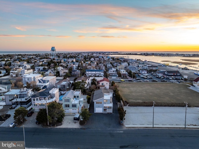 aerial view at dusk featuring a water view and a residential view