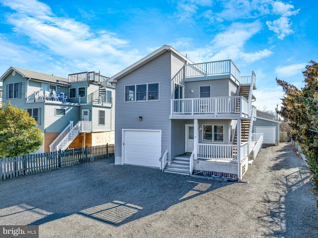 view of front of house with covered porch, fence, a balcony, a garage, and driveway