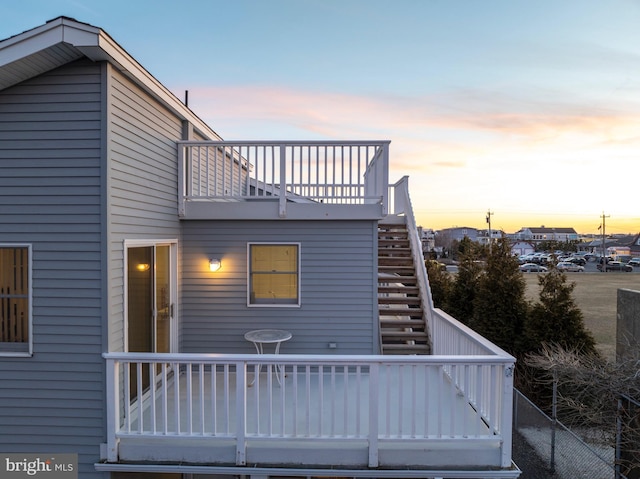 back of property at dusk featuring stairway and a deck