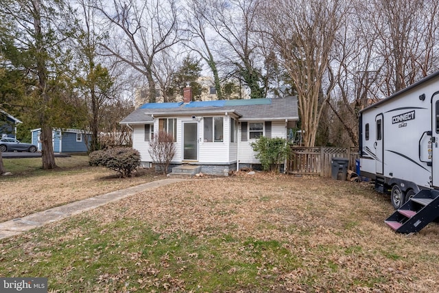 view of front facade with a front yard, fence, a chimney, and entry steps