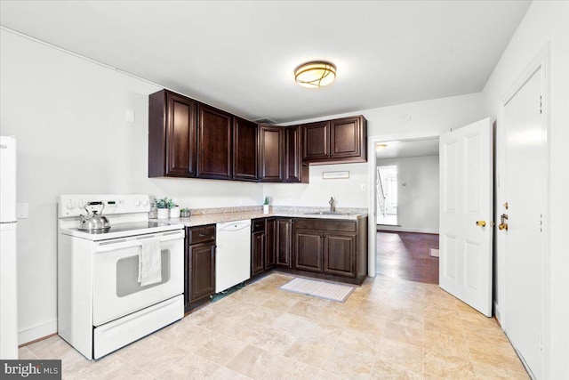 kitchen featuring dark brown cabinetry, white appliances, a sink, baseboards, and light countertops