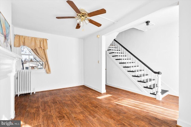 interior space featuring baseboards, radiator, ceiling fan, wood finished floors, and stairs