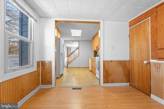 spare room with visible vents, a wainscoted wall, wood walls, and stairs