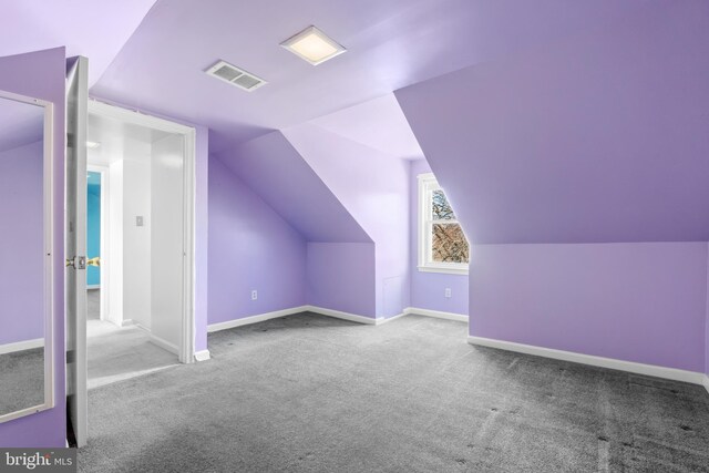 additional living space with vaulted ceiling, visible vents, baseboards, and carpet floors