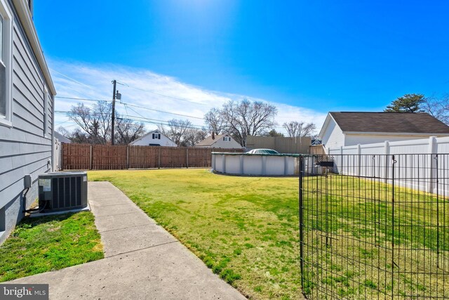 view of yard featuring a fenced in pool, central AC, and a fenced backyard