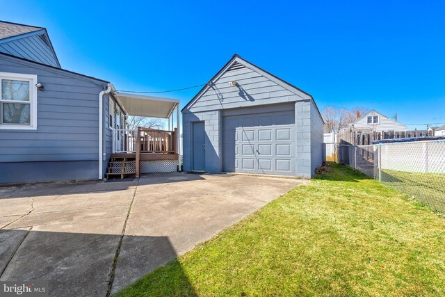 detached garage featuring concrete driveway and fence